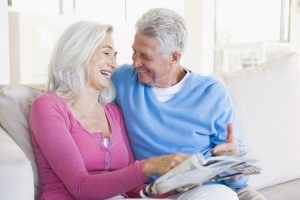 Elderly Caucasian Couple Laughing on the Couch while Reading a Magazine