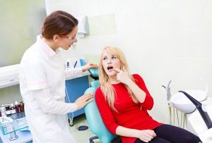 Young Woman Pointing to her Mouth to Show Dentist Source of the Problem