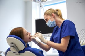 Female Dental Assistant Examining Patient